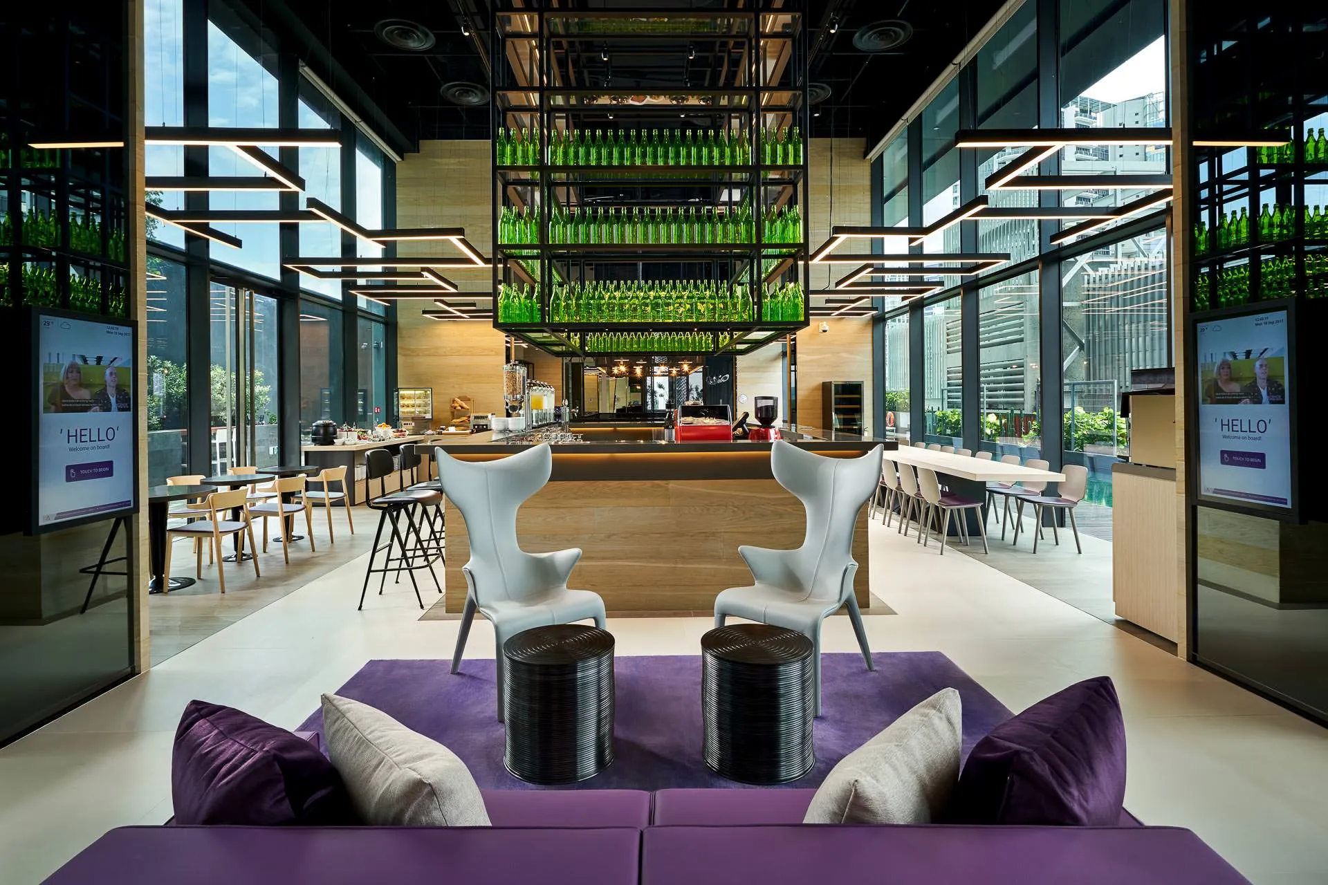 Hotel lobby with purple sofas, welcome screens and glass bottle chandelier — YOTEL Singapore interior photography