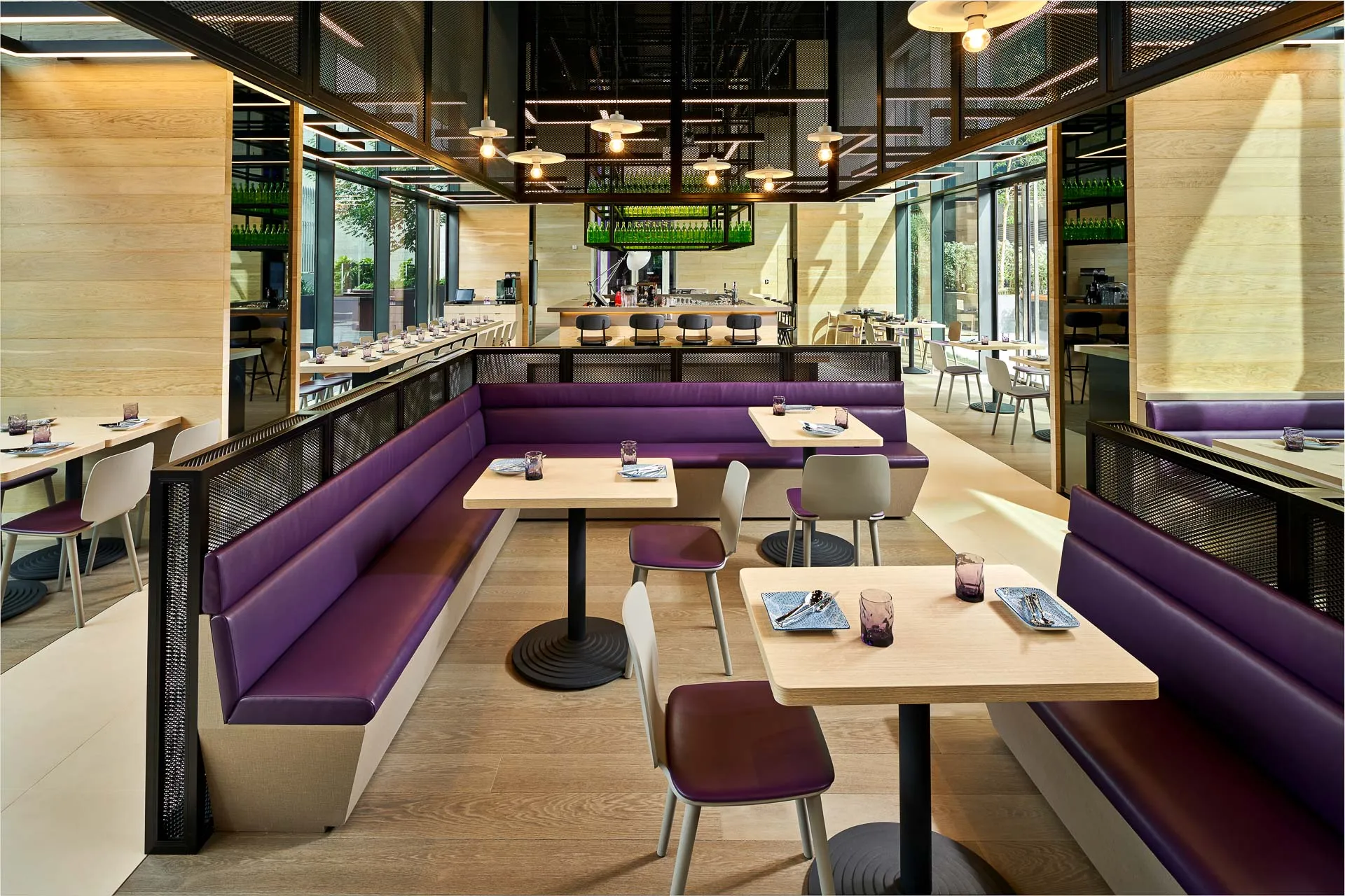 Restaurant with purple banquette seating, oak tables and open kitchen — YOTEL Singapore interior photography