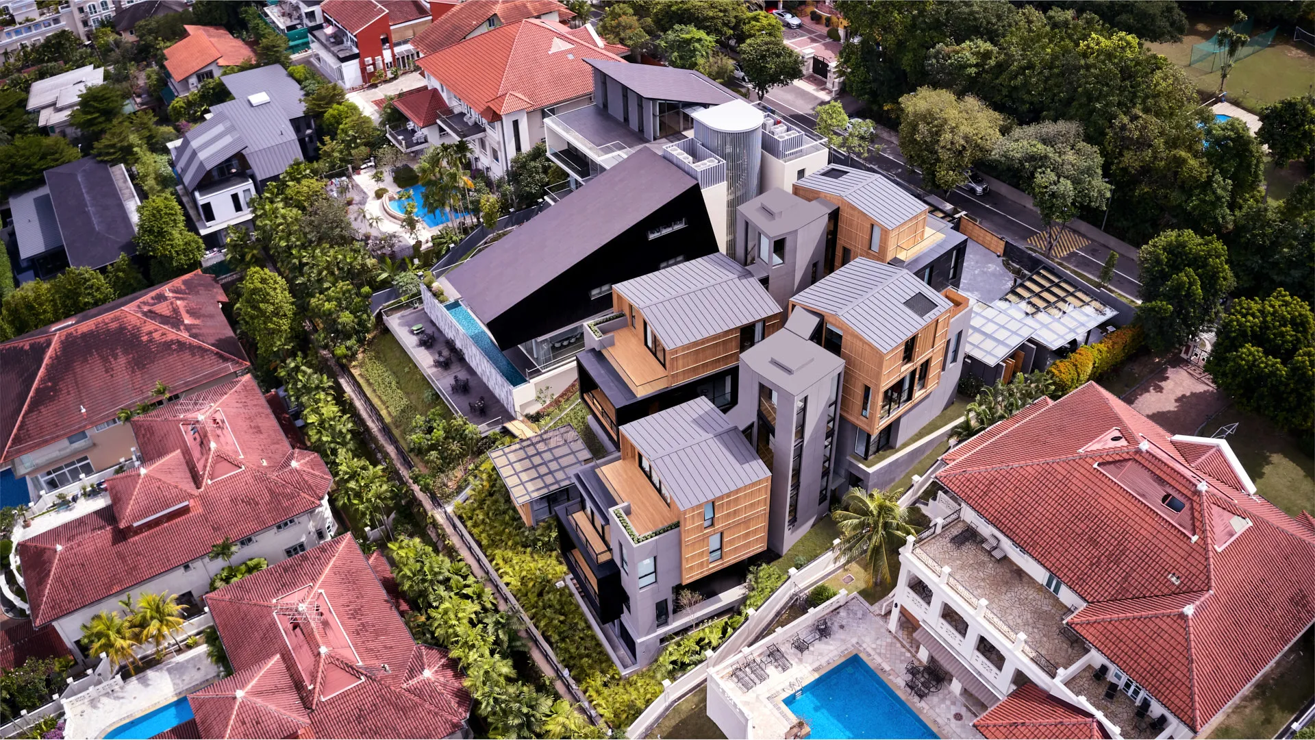 Oblique aerial showing dark angular wing, pool terrace and timber volumes — 32 House Singapore drone photography