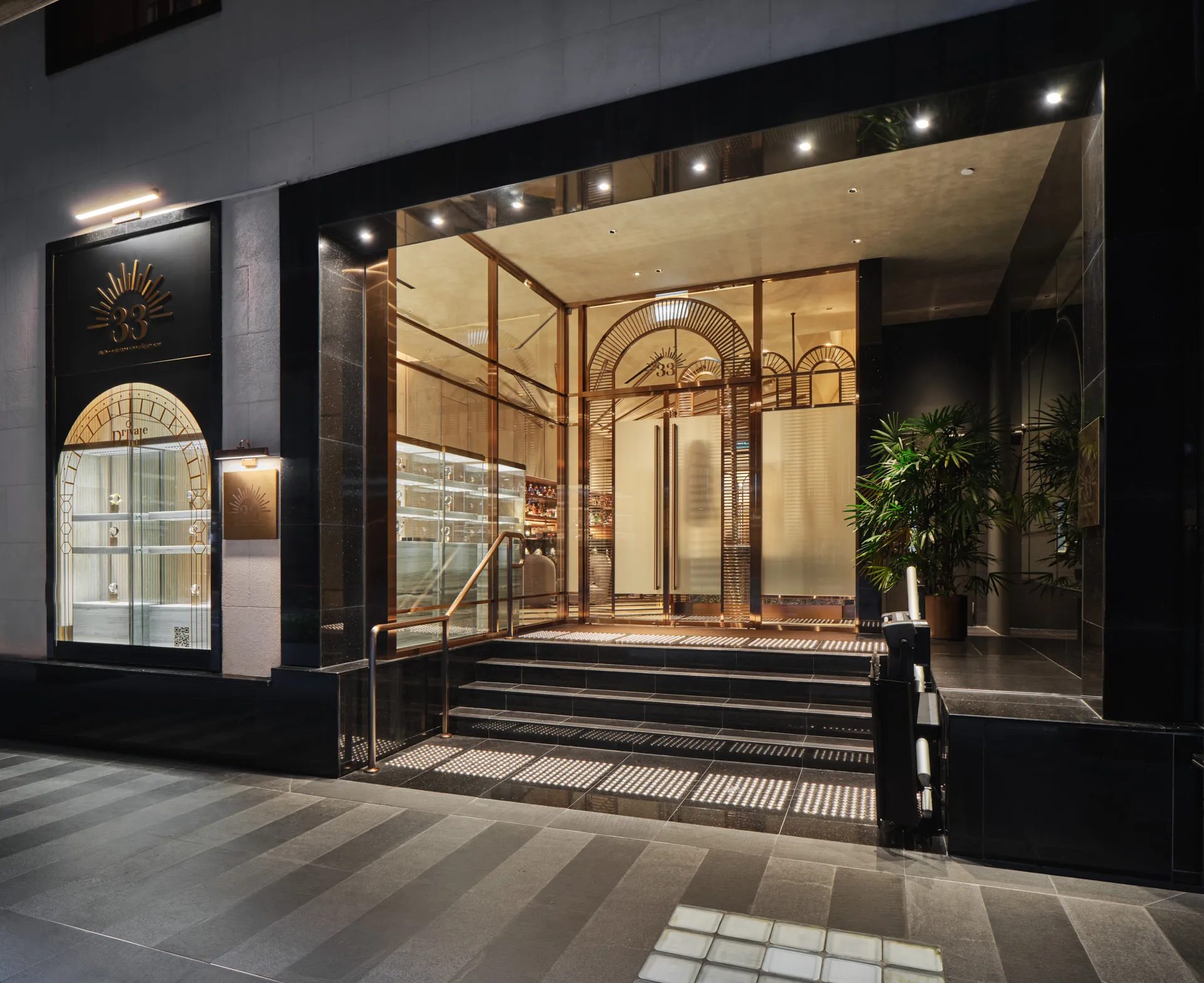 Art Deco entrance with black granite, sunburst brass logo and copper rails — 33 Club Singapore architectural photography