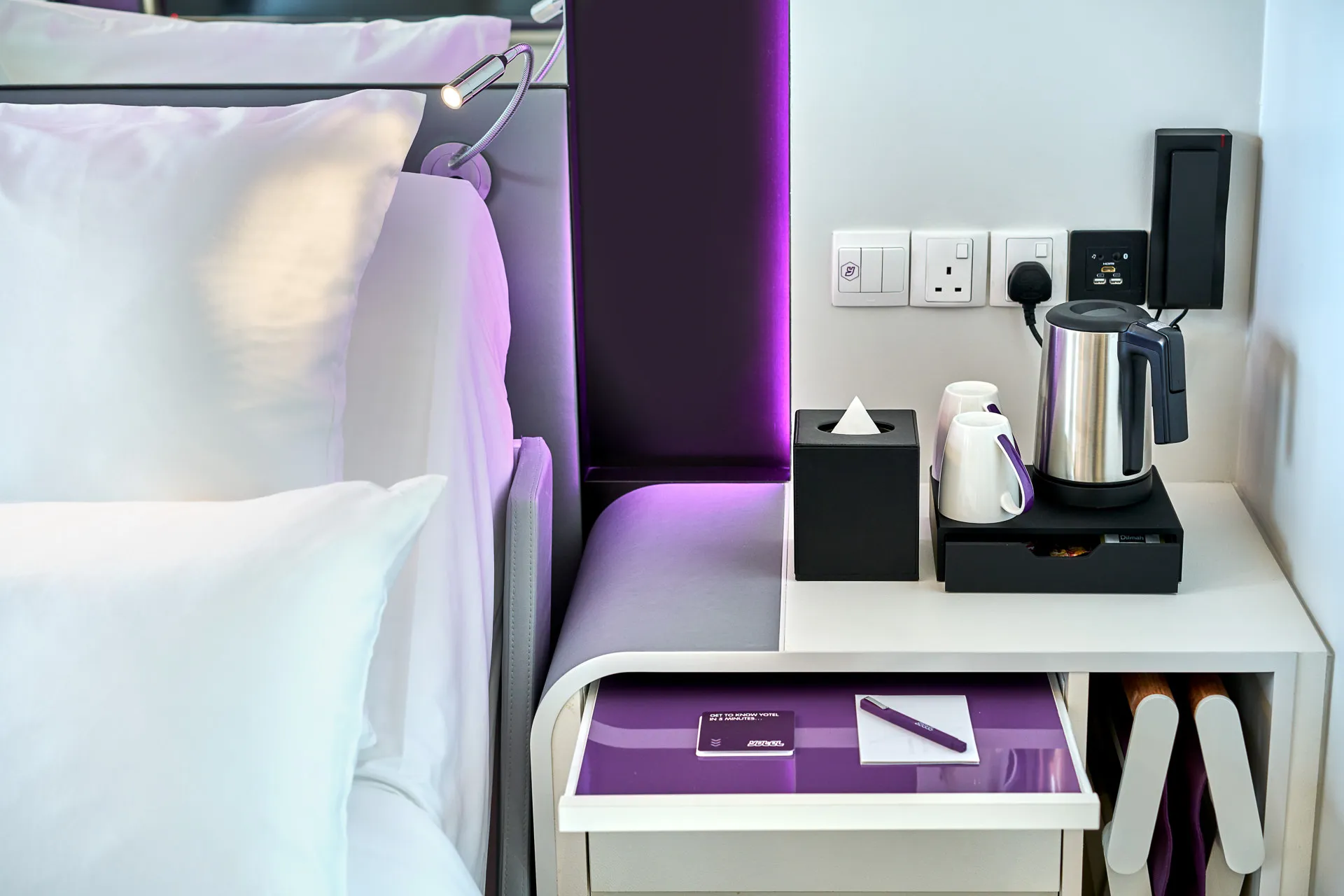 Bedside detail with kettle, tea set and purple LED headboard — YOTEL Singapore interior photography