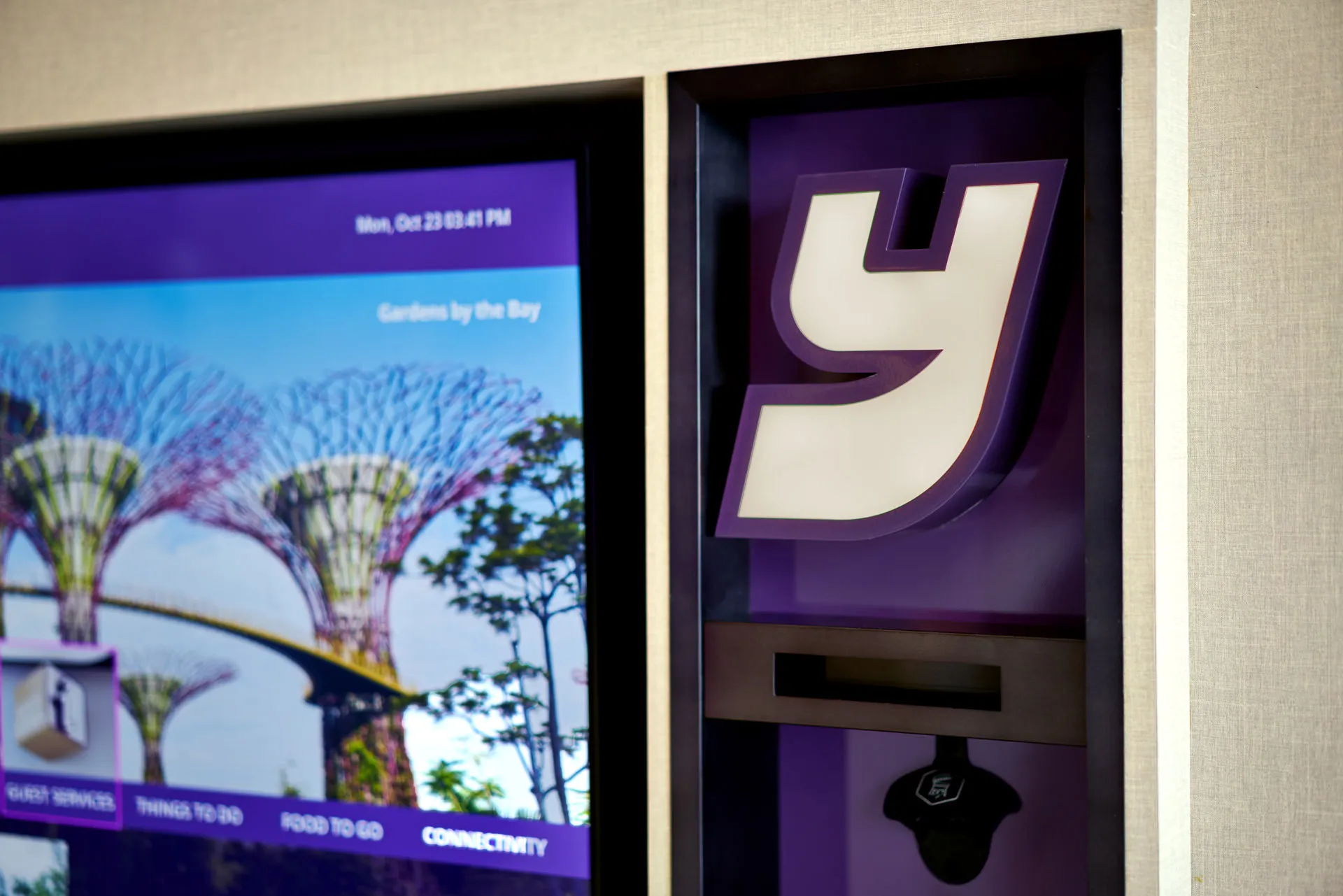 Self-service kiosk touchscreen with Gardens by the Bay and Y brand logo — YOTEL Singapore hotel photography