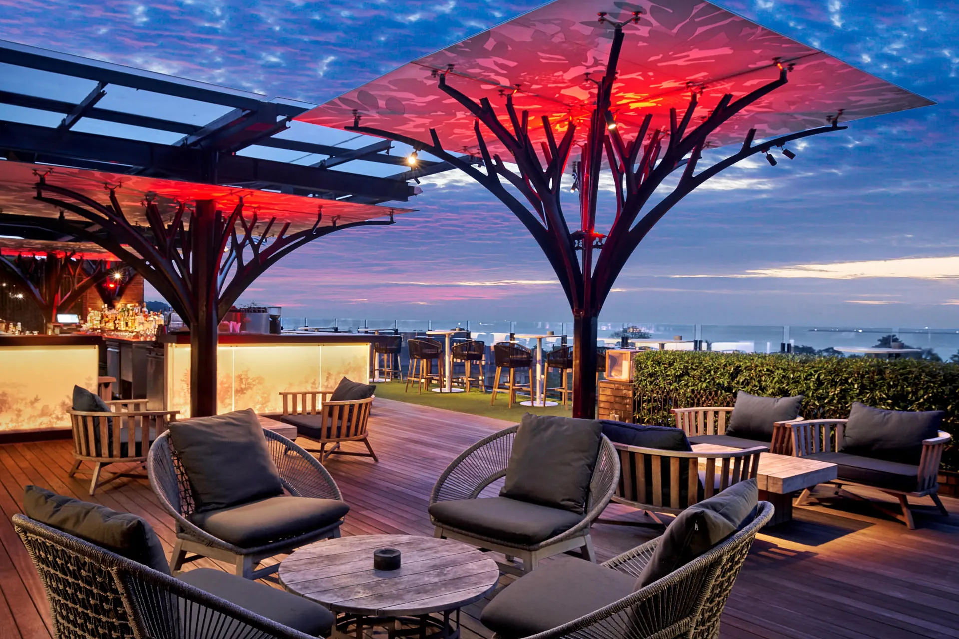 Twilight terrace with rope chairs and red-lit canopy against sunset sky — Above Eleven Bali restaurant photography