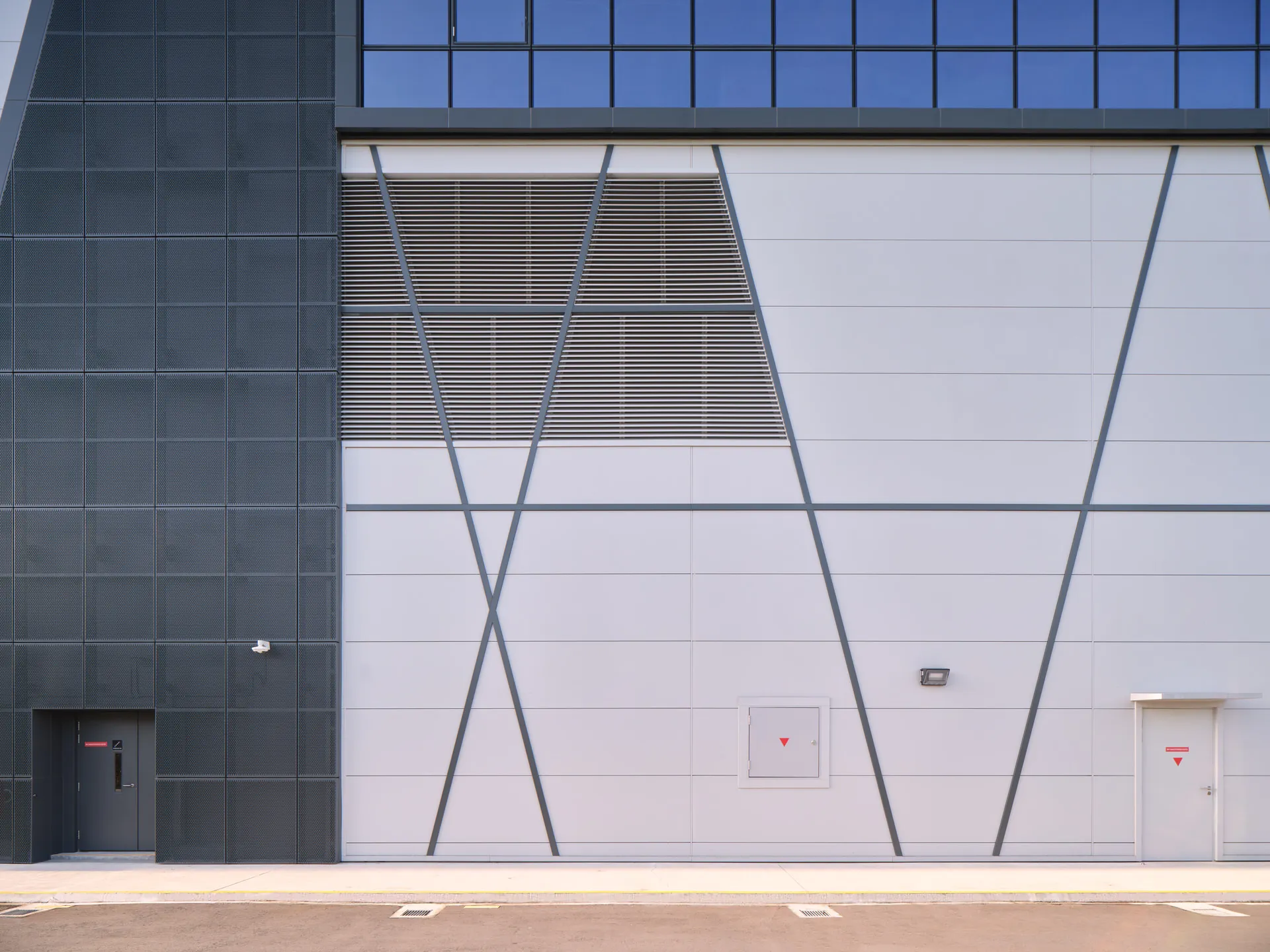 Perforated metal and white panel cladding detail with angular seams — Trimo Qbiss One Singapore facade photography