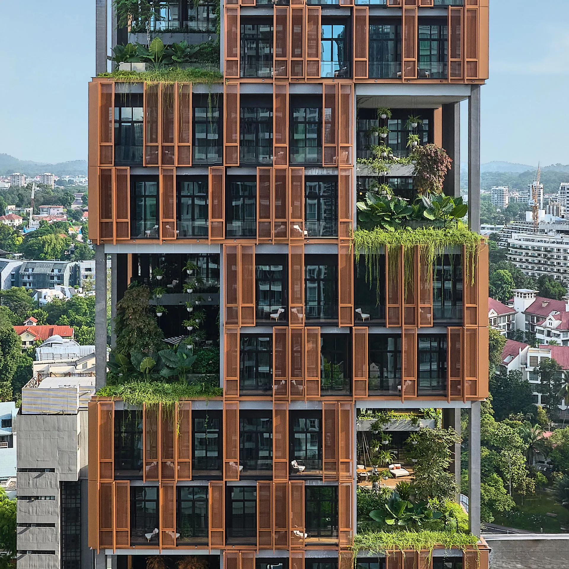 Facade detail with copper screens, sky terraces and cascading tropical planting — Artyzen Singapore drone photography