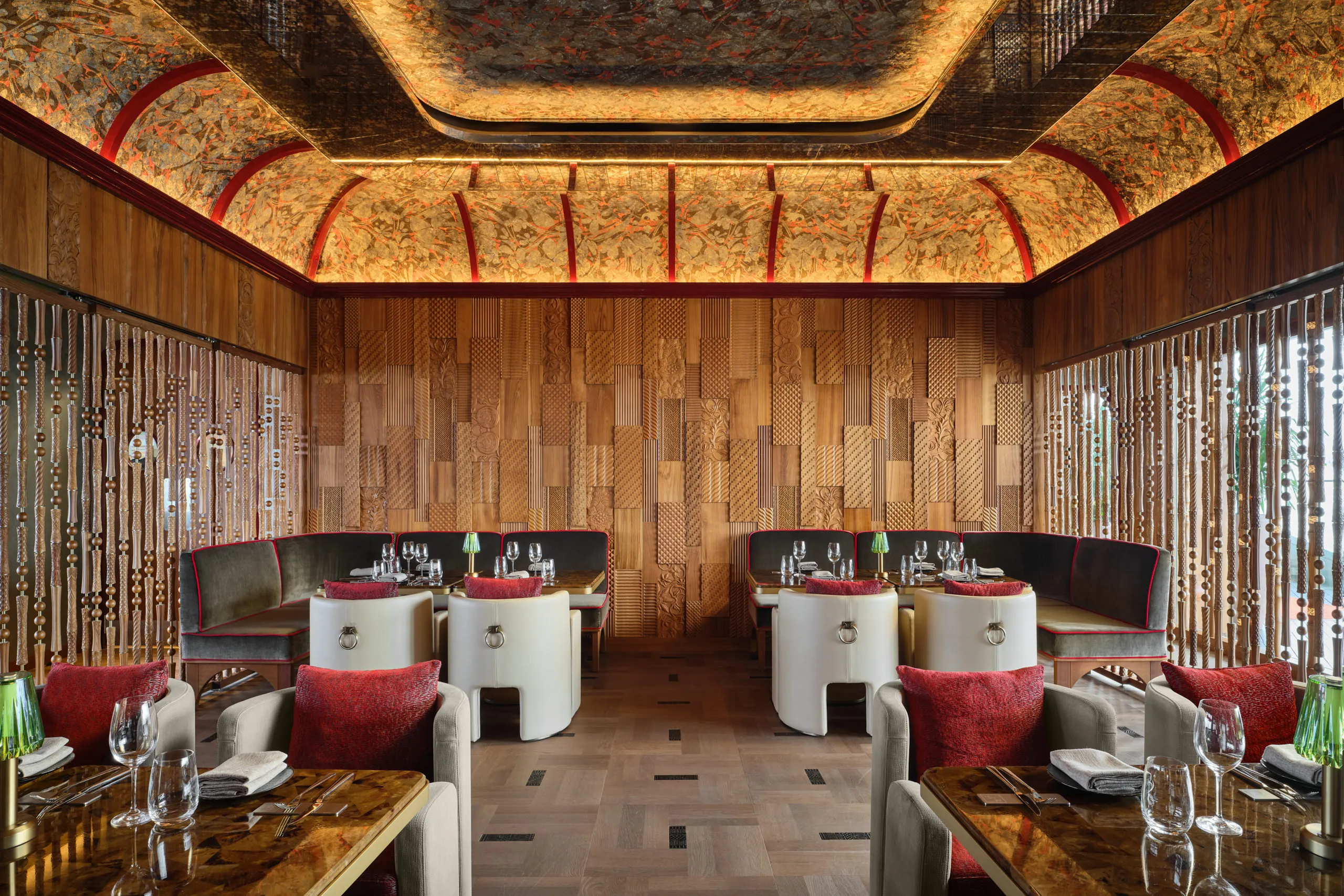 Detailed interior photograph of a private dining nook at CÉ LA VI Singapore, showcasing the rich textures of the red banquette seating and ornate woodwork.