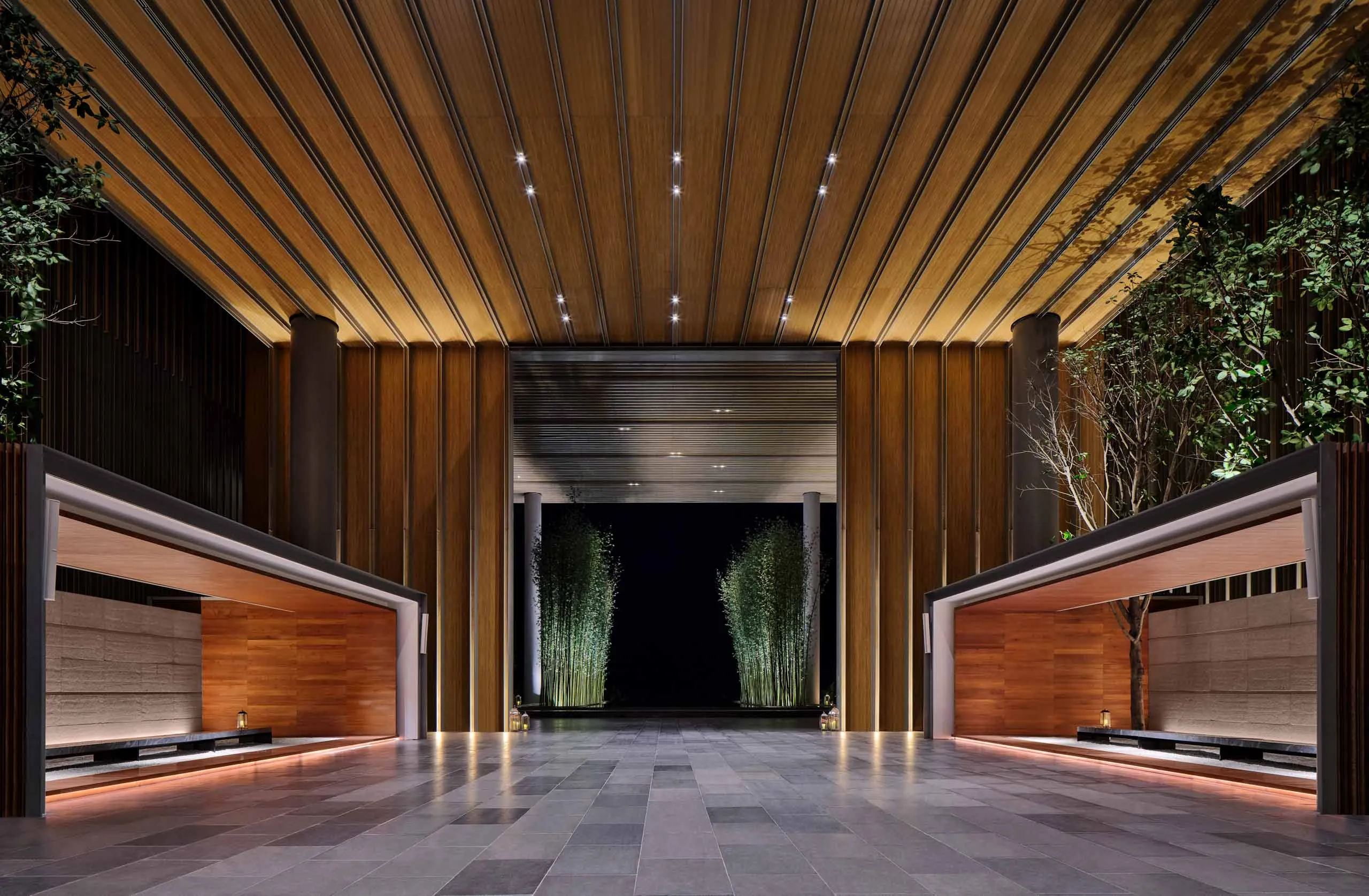 Timber-slatted porte-cochere with bamboo groves and dramatic uplighting — The Sanya Edition Hainan China architectural photography