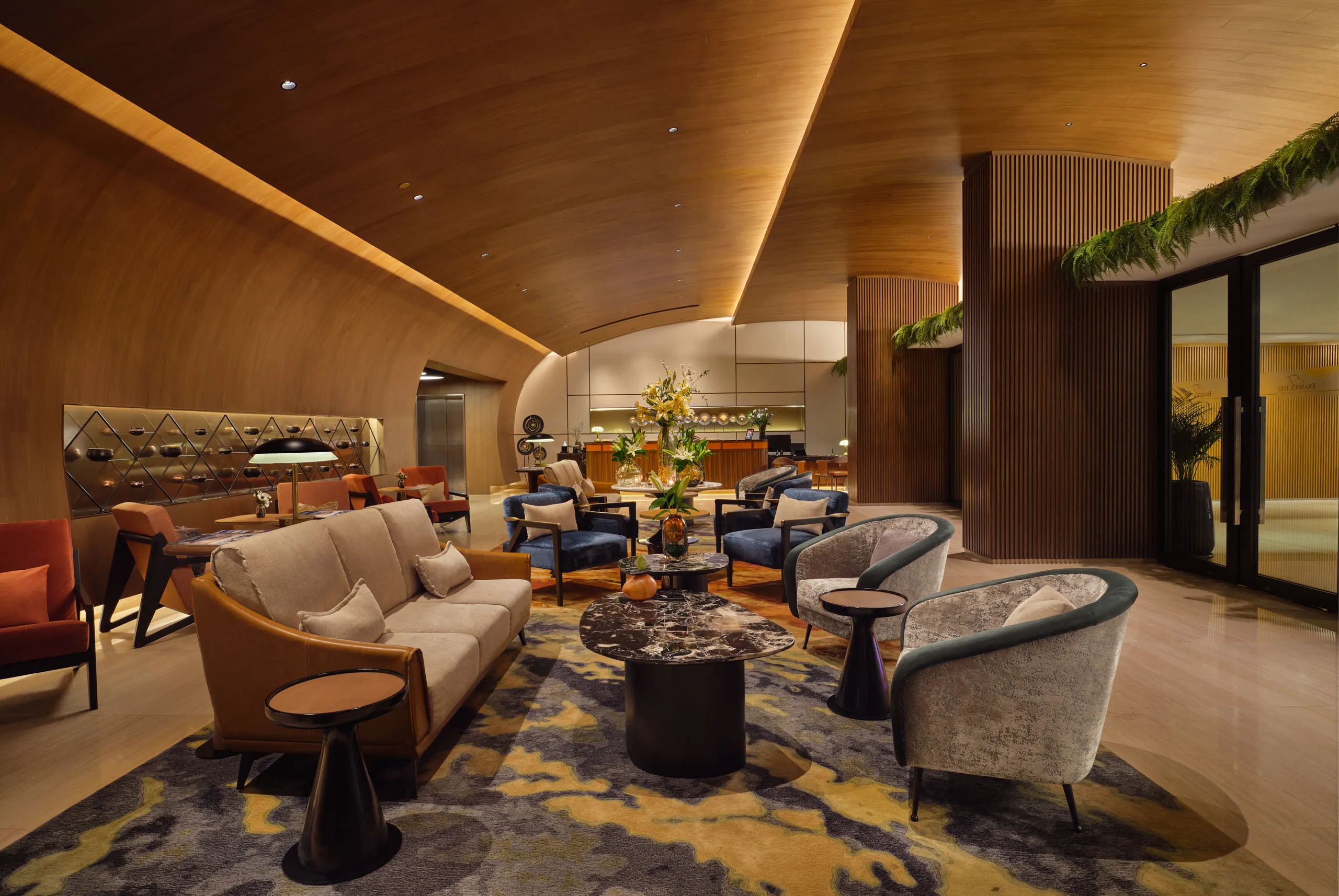 Fraser Suites Sukhumvit lobby lounge with velvet armchairs and sculptural wood ceiling