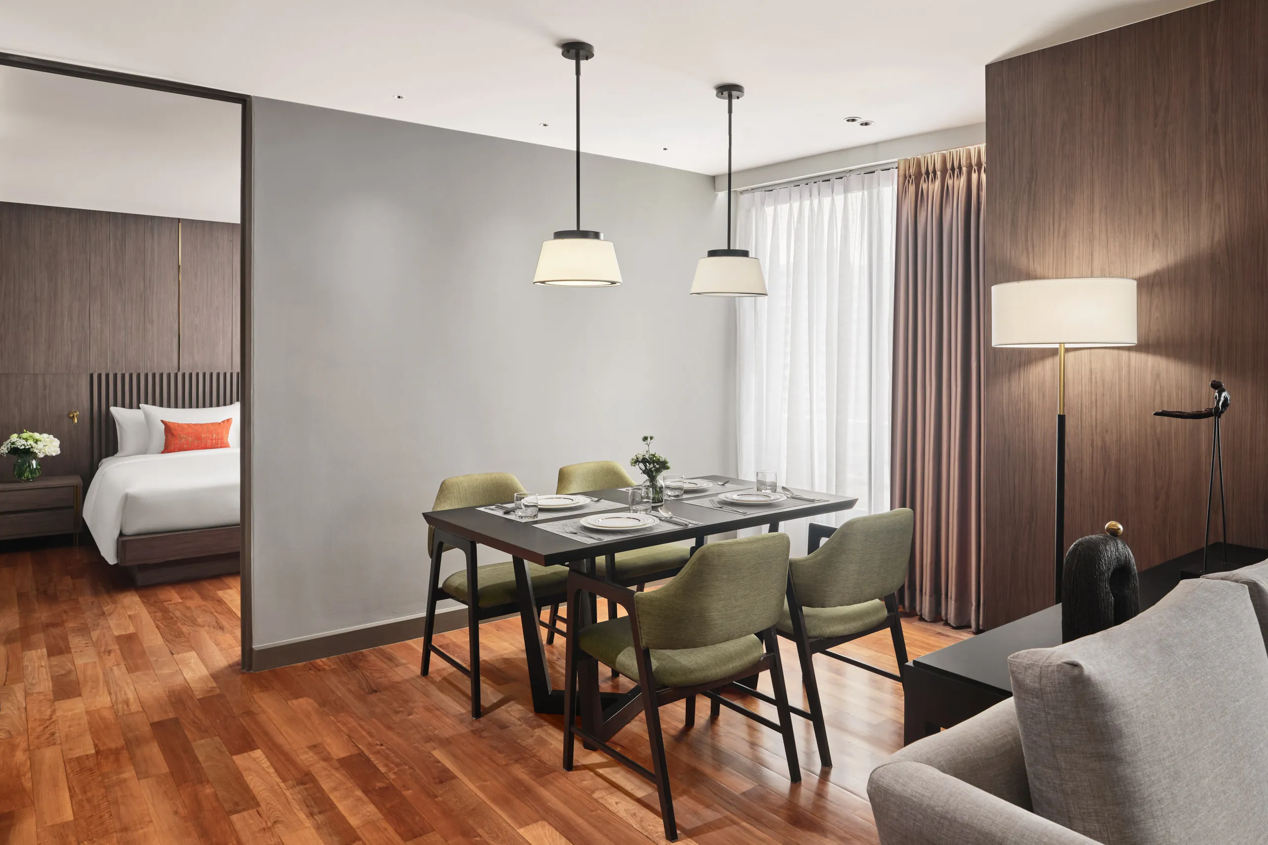 Suite dining area with olive chairs, twin pendants and bedroom beyond — Fraser Suites Sukhumvit interior photography