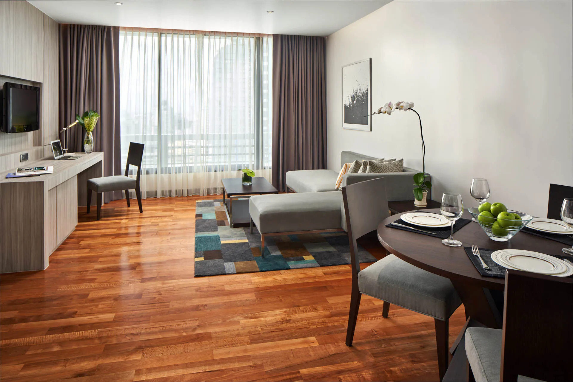 Living-dining area with grey sectional, teal rug and dining table — Fraser Suites Sukhumvit Bangkok interior photography