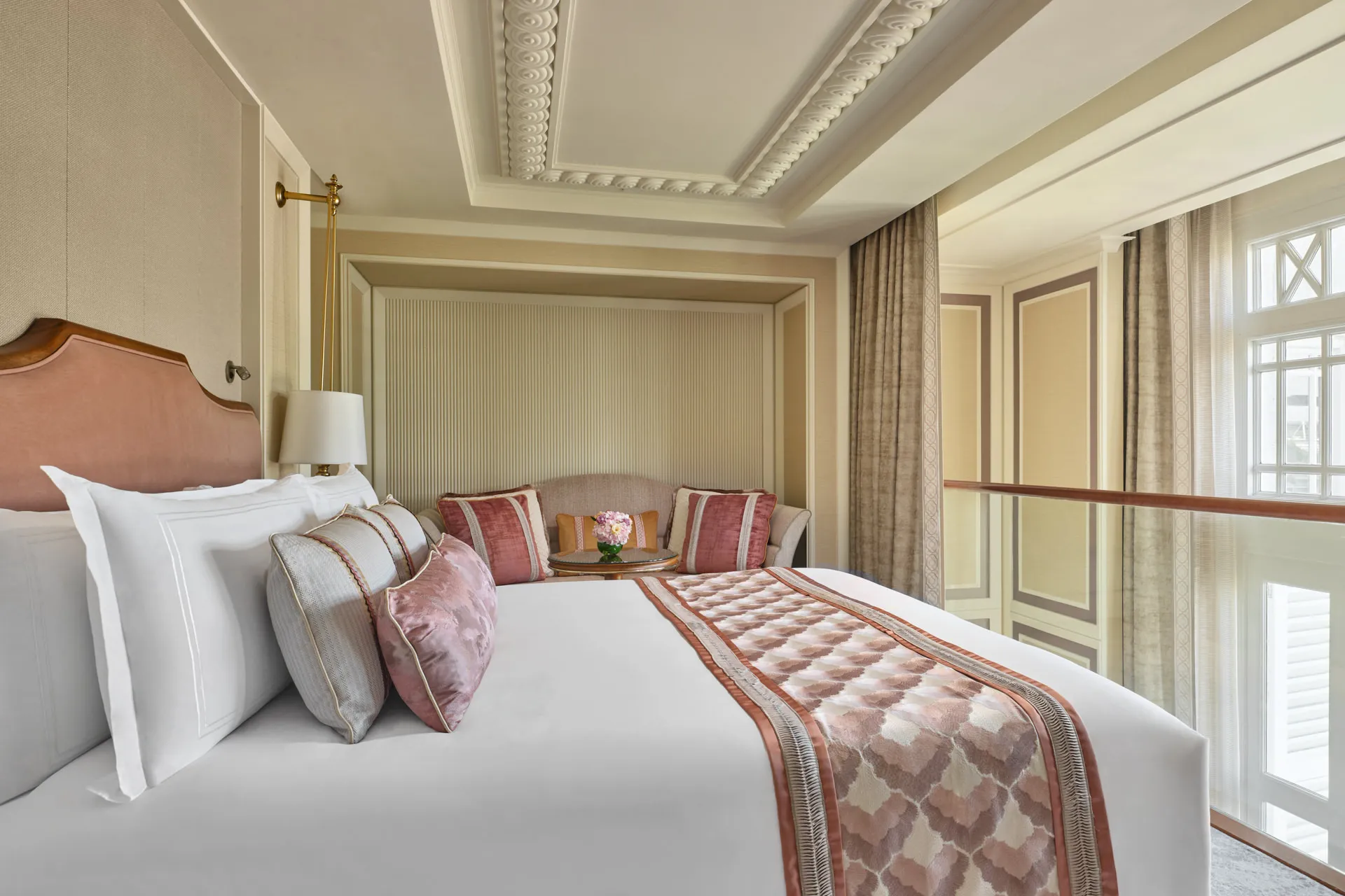 Coral bedroom with scallop throw, velvet cushions and brass reading lamp — Fullerton Hotel Singapore hotel photography