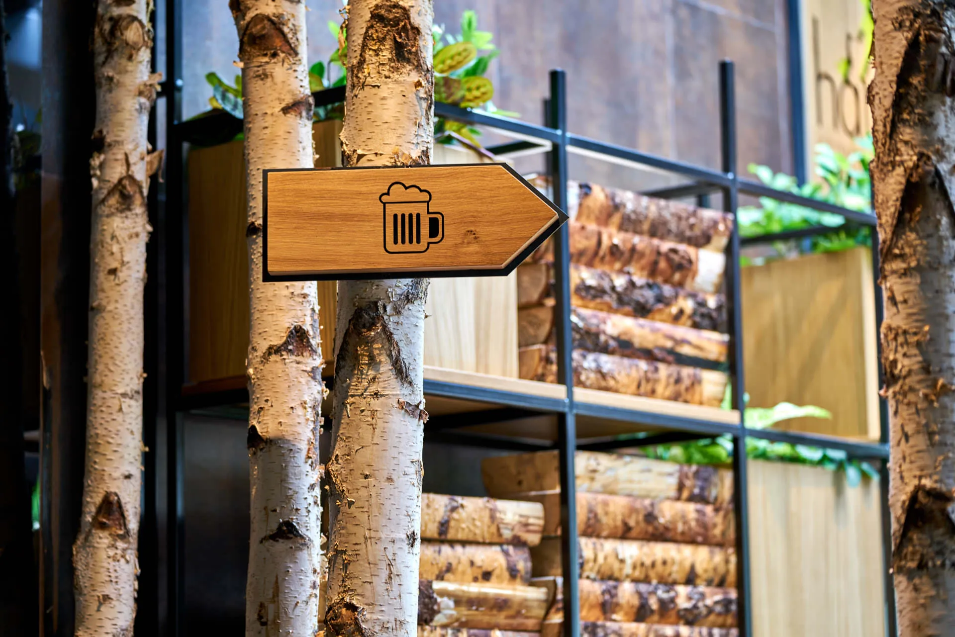 Restaurant photography detail of a rustic wooden sign and decorative stacked logs, central to Hans Im Gluck's unique WOLF-designed interior.