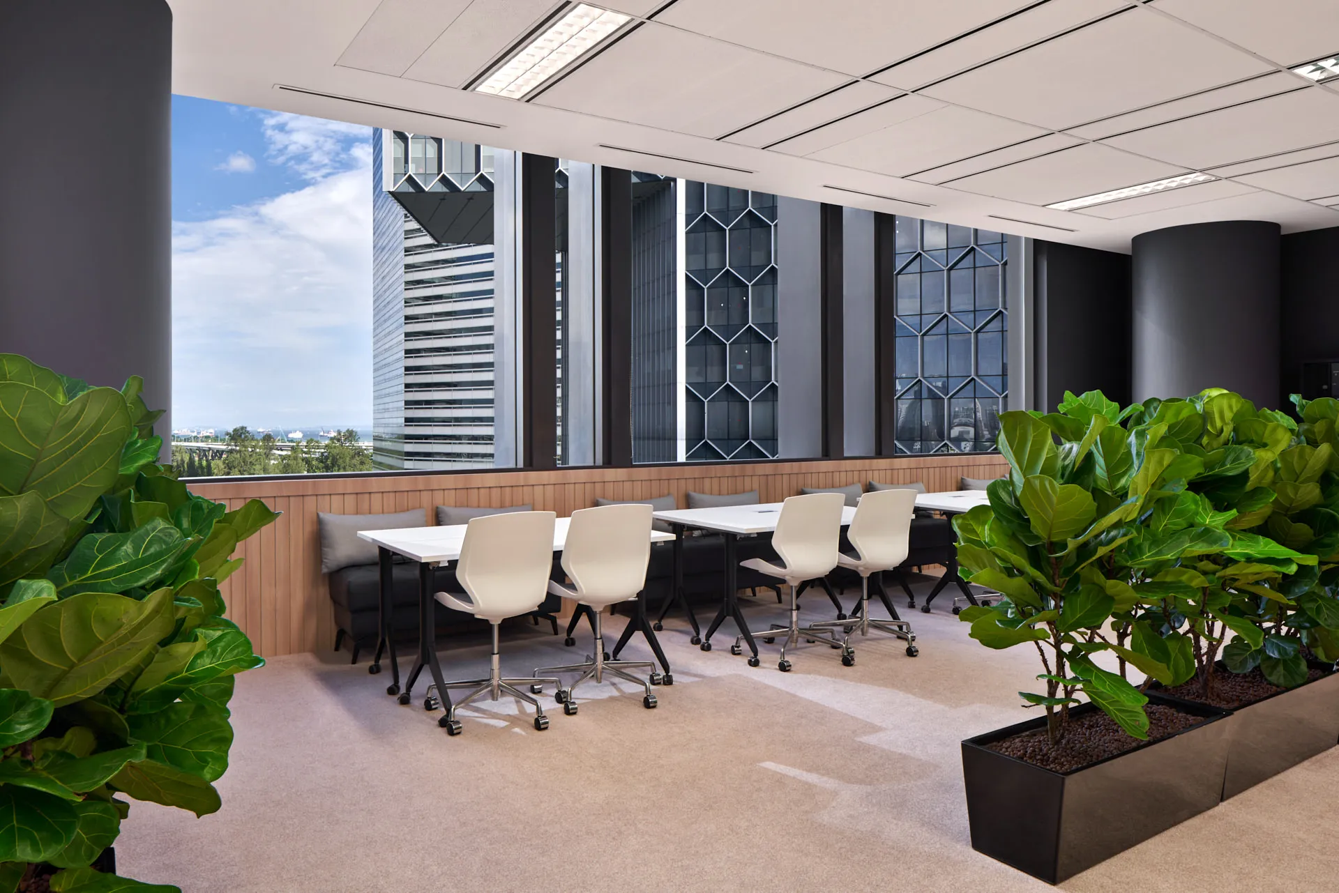 Window banquette seating with biophilic planters and city views — JCO Singapore workplace photography