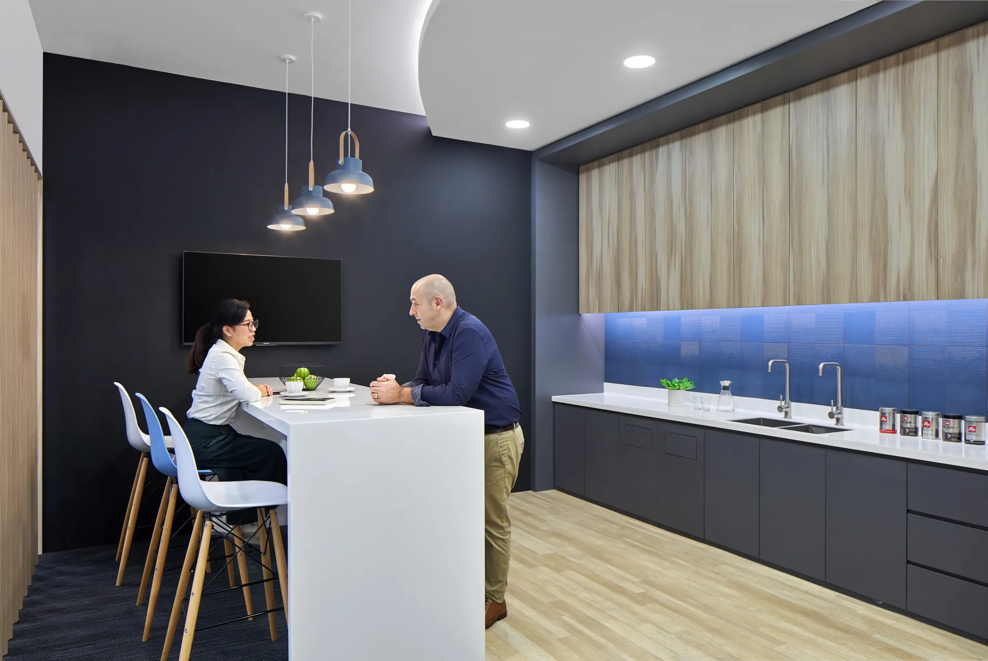 Office pantry with navy feature wall and blue pendant lamps — King Wood Mallesons Singapore workplace photography