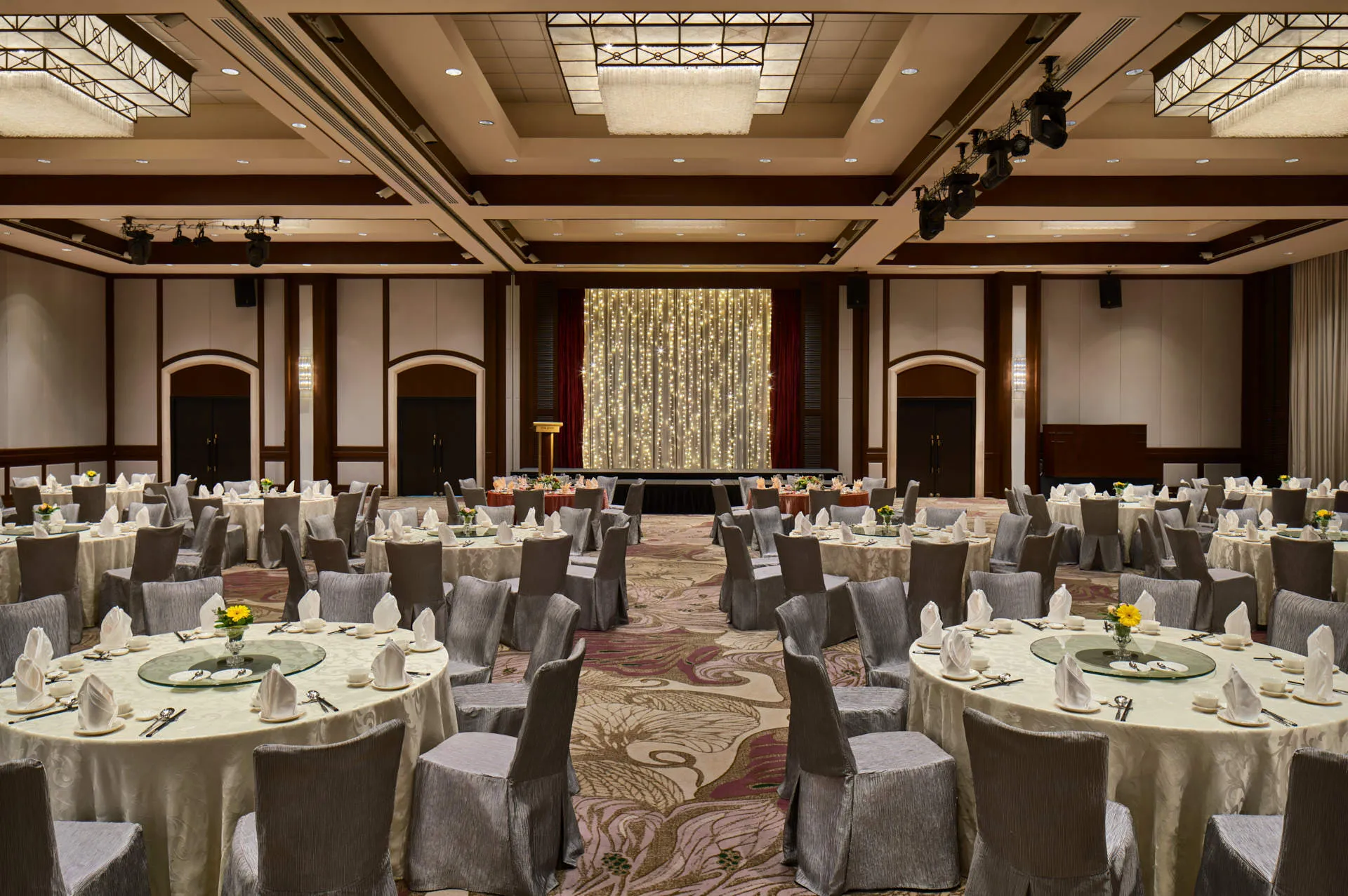 Dinner and dance banquet with silver chairs, floral centrepieces and fairy-light stage — Paradox Singapore ballroom photography