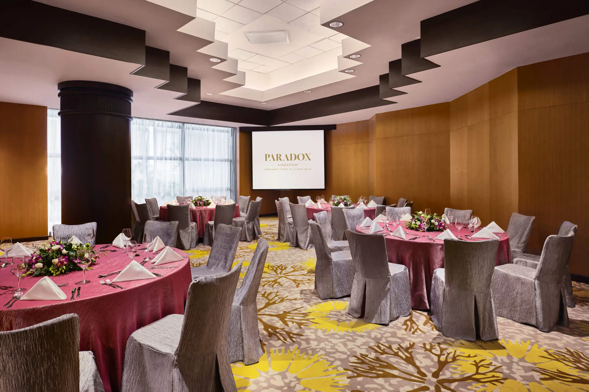 Dinner event with magenta linens, floral centrepieces and tiered ceiling — Paradox Singapore function room photography