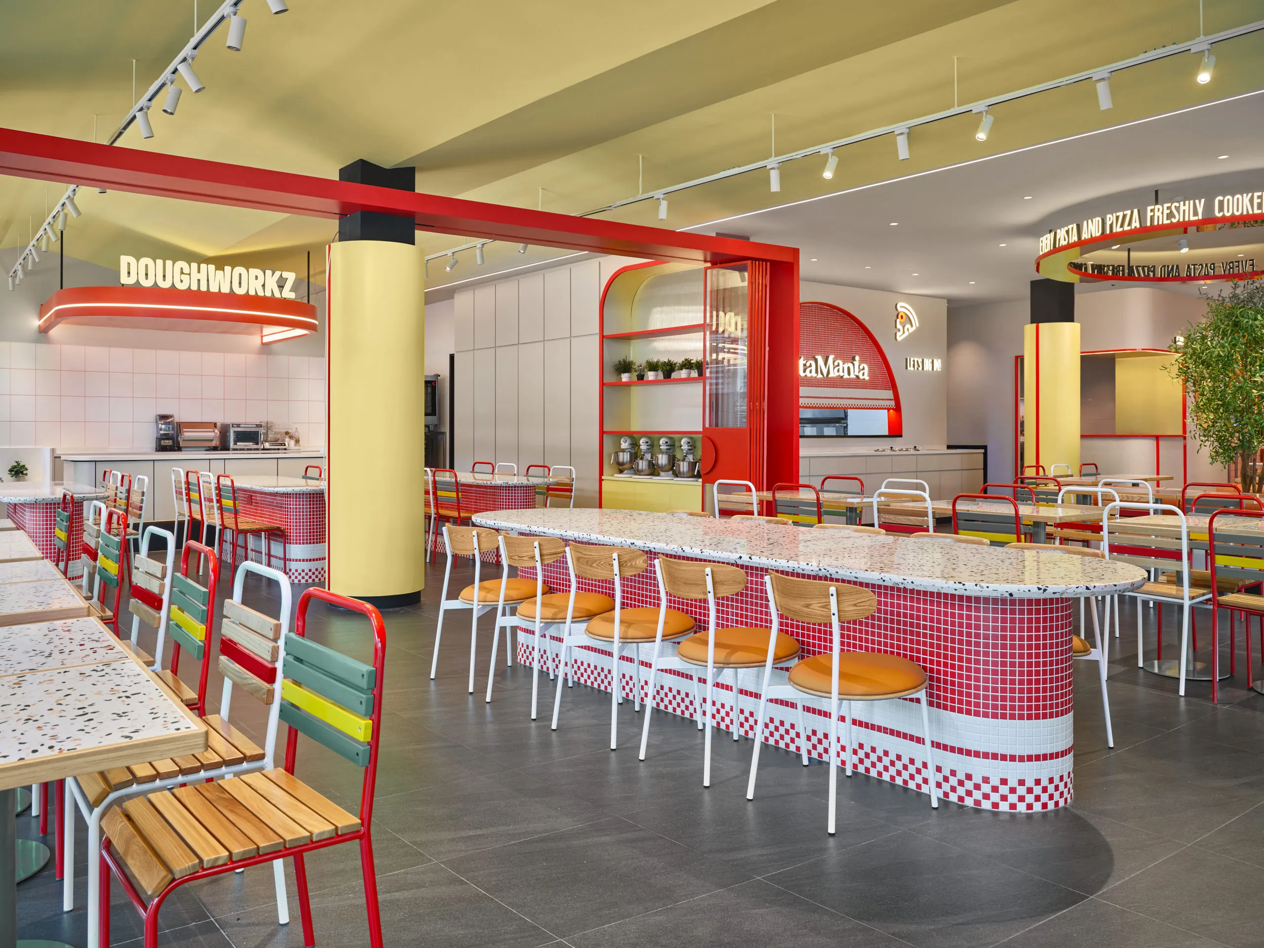 Doughworkz workshop zone with oval mosaic tables and arched display cabinet — PastaMania restaurant photography