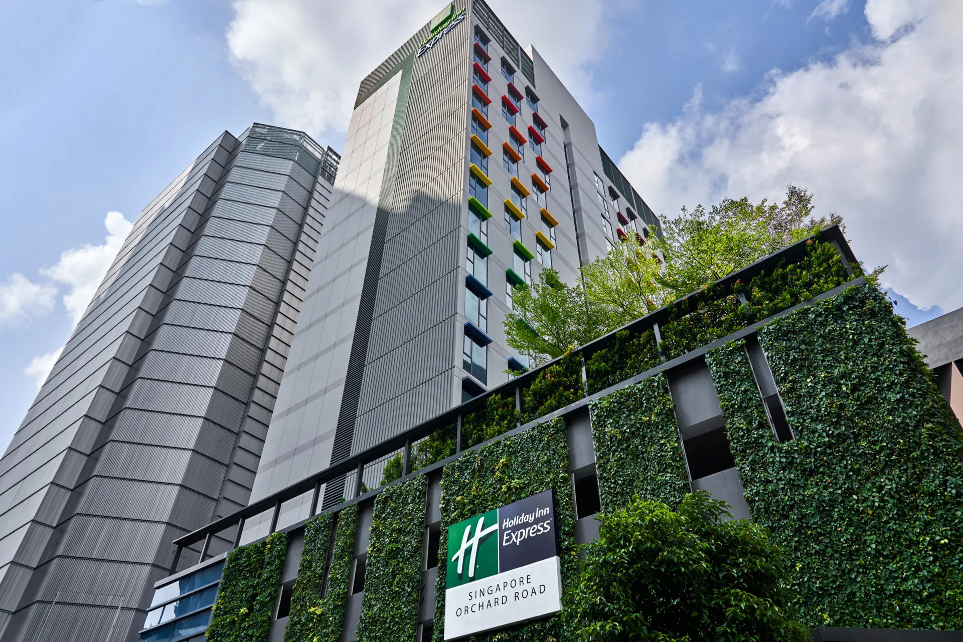 Hotel tower with colourful window awnings and living wall entrance — Holiday Inn Express Orchard architectural photography