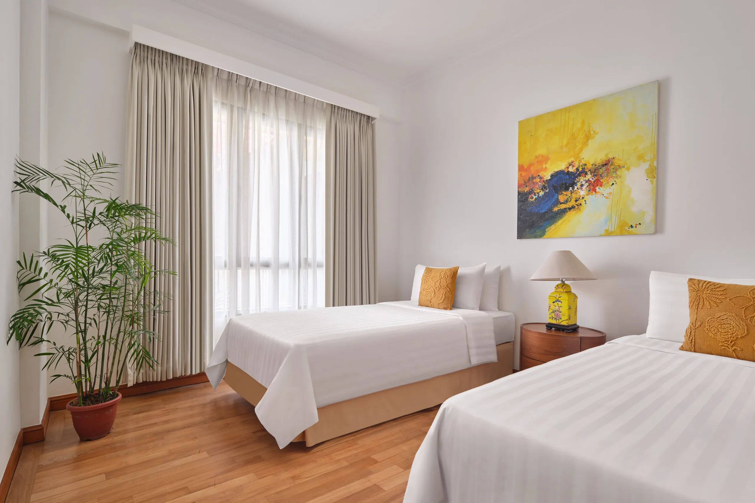 Twin bedroom with white linens, yellow accent art and palm plant, Shangri-La Residences Singapore, hospitality photography