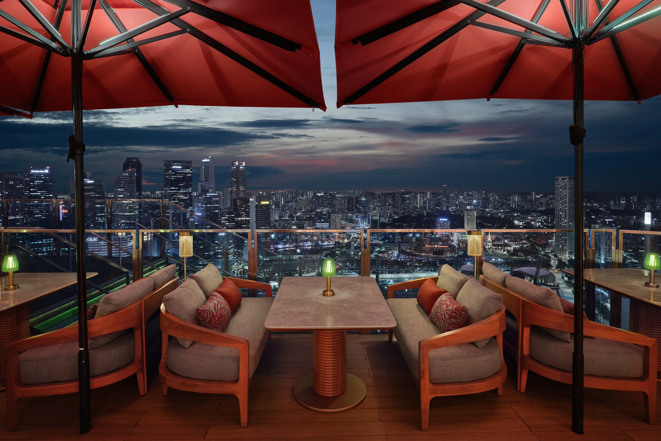 Lifestyle interior photography capturing a detailed seating vignette at CÉ LA VI's rooftop bar at dusk, showcasing the mood against the Singapore skyline.