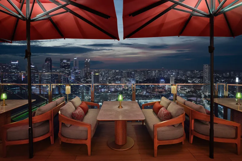 Lifestyle interior photography capturing a detailed seating vignette at CÉ LA VI's rooftop bar at dusk, showcasing the mood against the Singapore skyline.