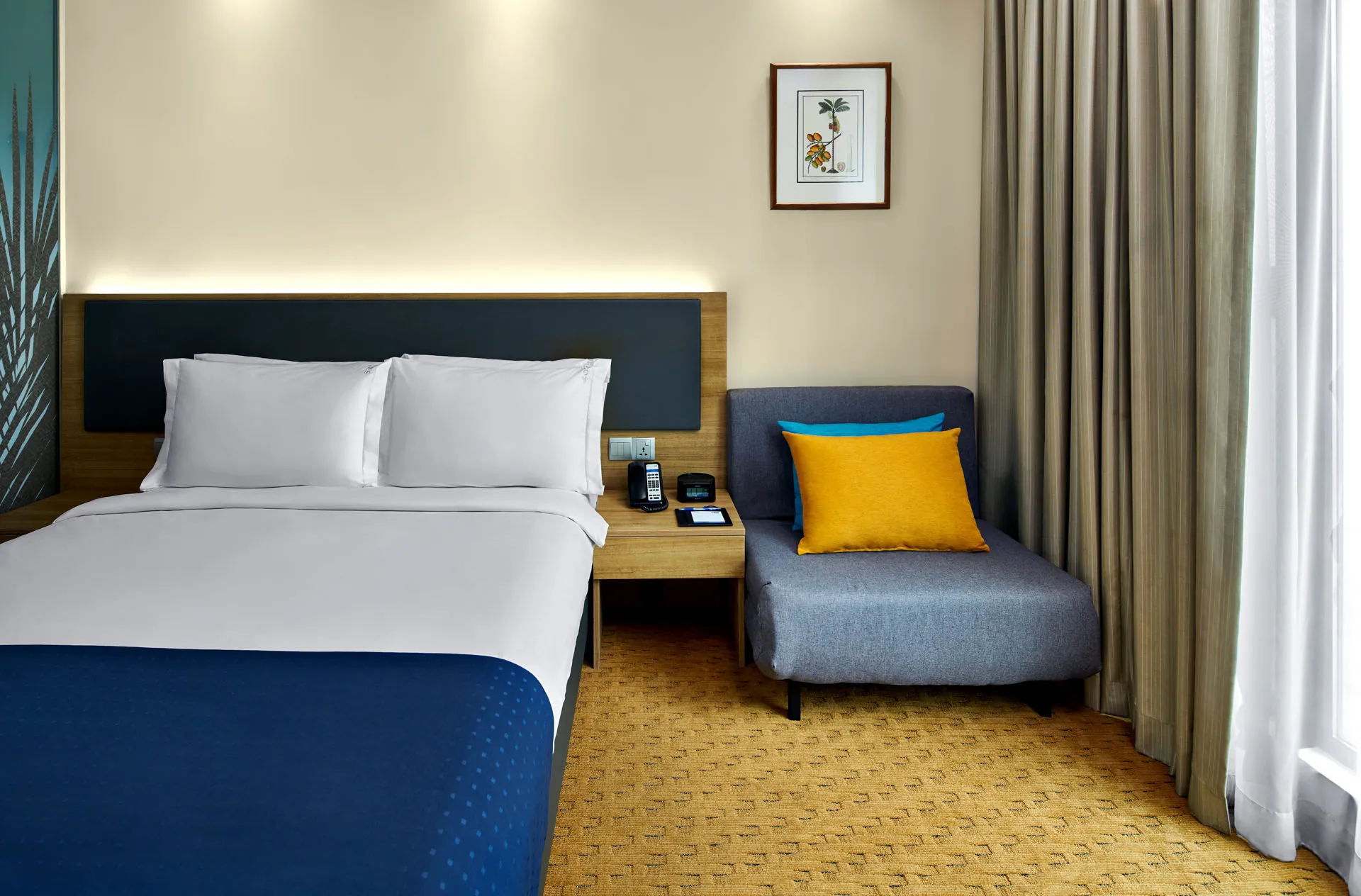 Bedside detail with yellow pillow armchair and LED headboard lighting — Holiday Inn Express Orchard hotel photography