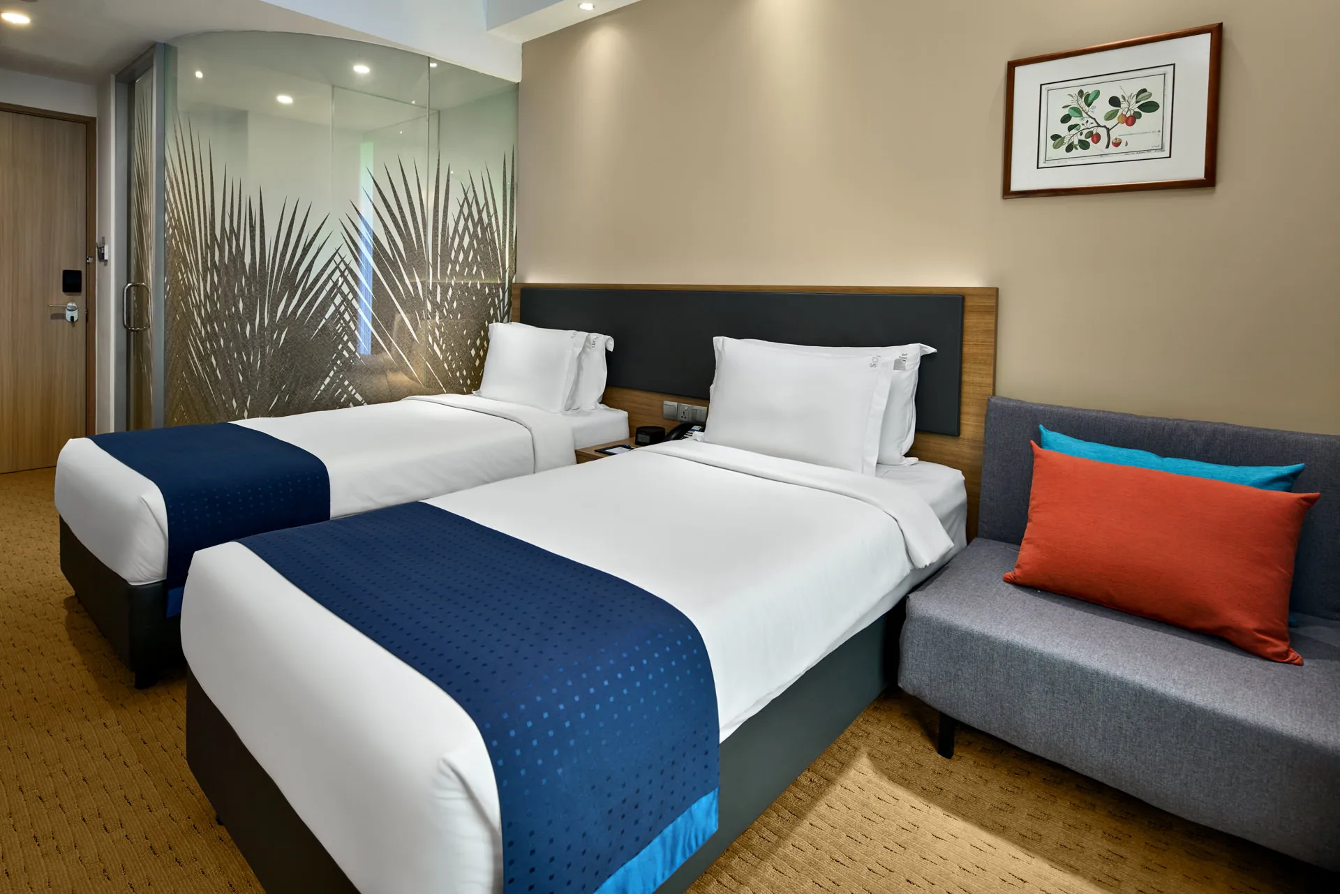 Twin room with sofa, frosted palm-leaf bathroom partition and botanical art — Holiday Inn Express Orchard hotel photography