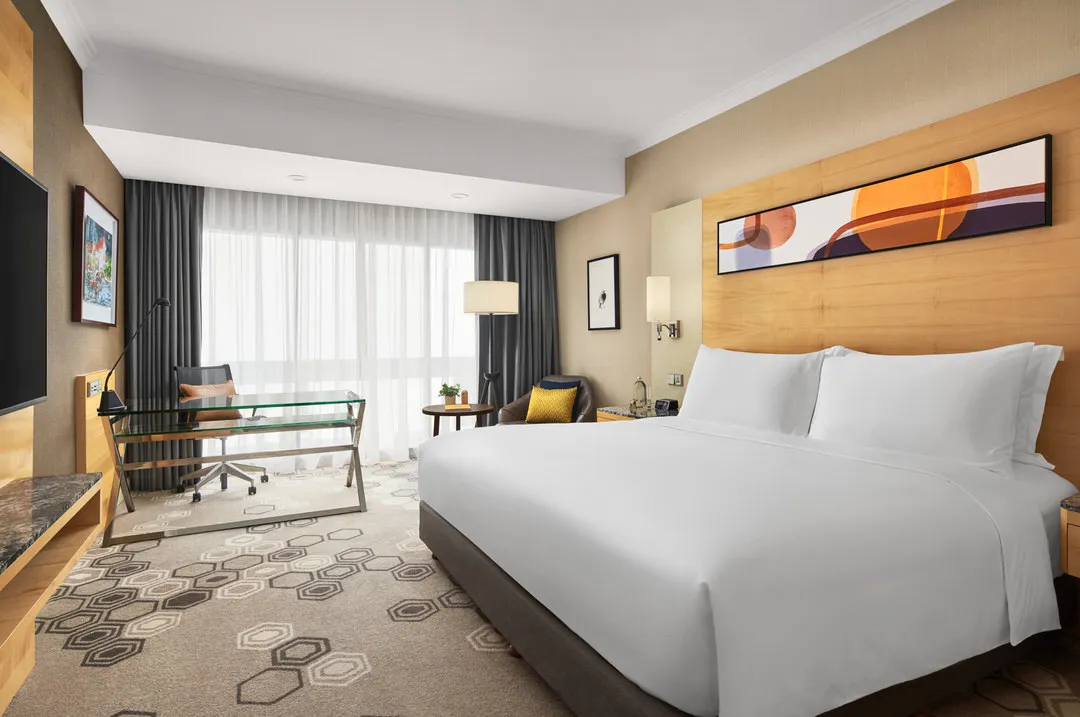 King room with light wood headboard, abstract art and leather armchair — voco Orchard Singapore hotel photography