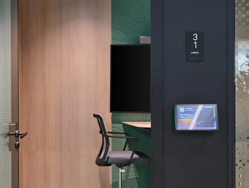 A detailed close-up of the glass office pod, highlighting the sleek black door handle and the modern design of the chair inside. This shot emphasizes the quality materials used in the CBRE workplace, a key focus in corporate interior photography.