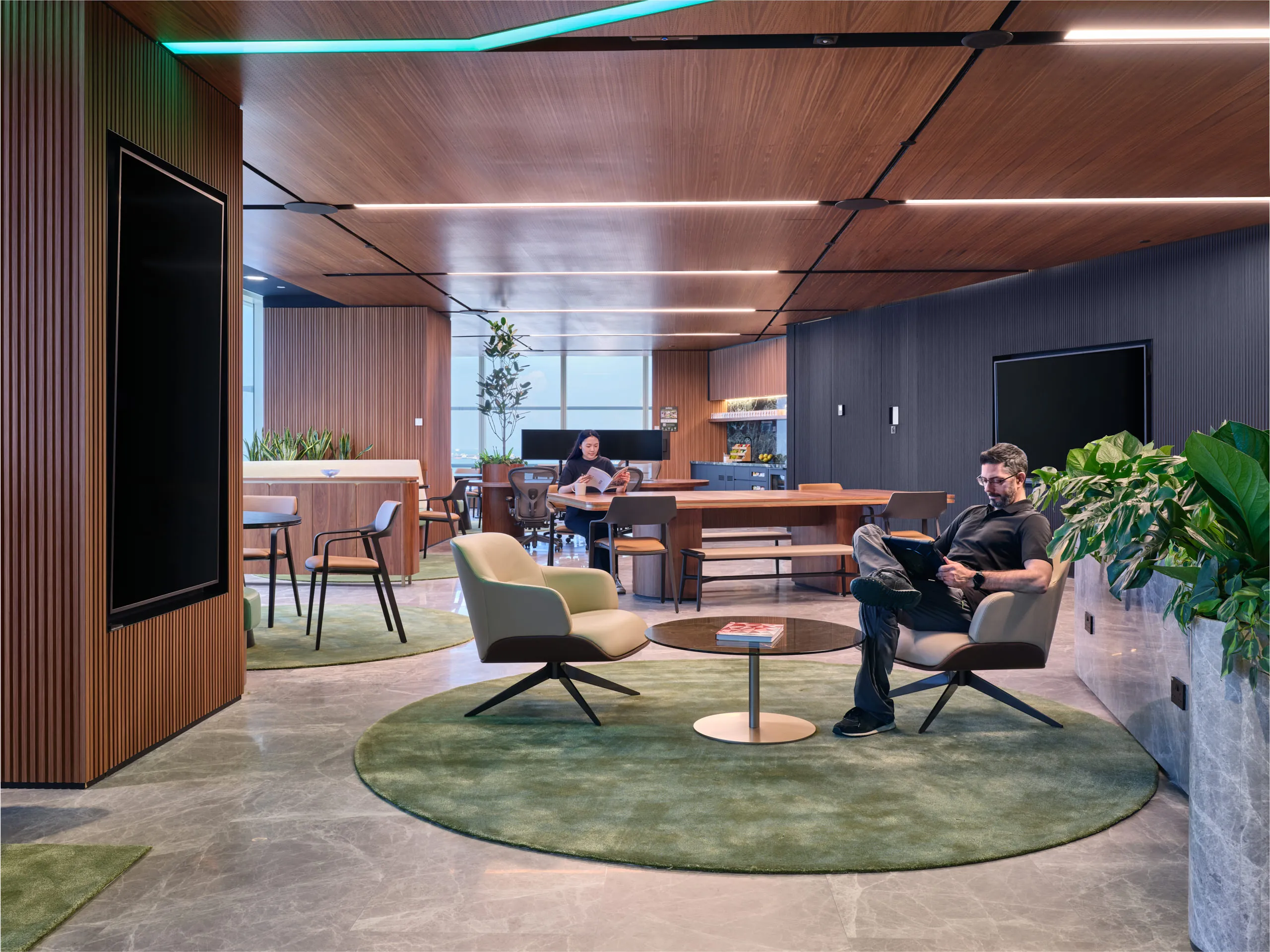 Elegant office breakout space designed with a circular rug and a unique statement light fixture, highlighting modern workplace interior design.