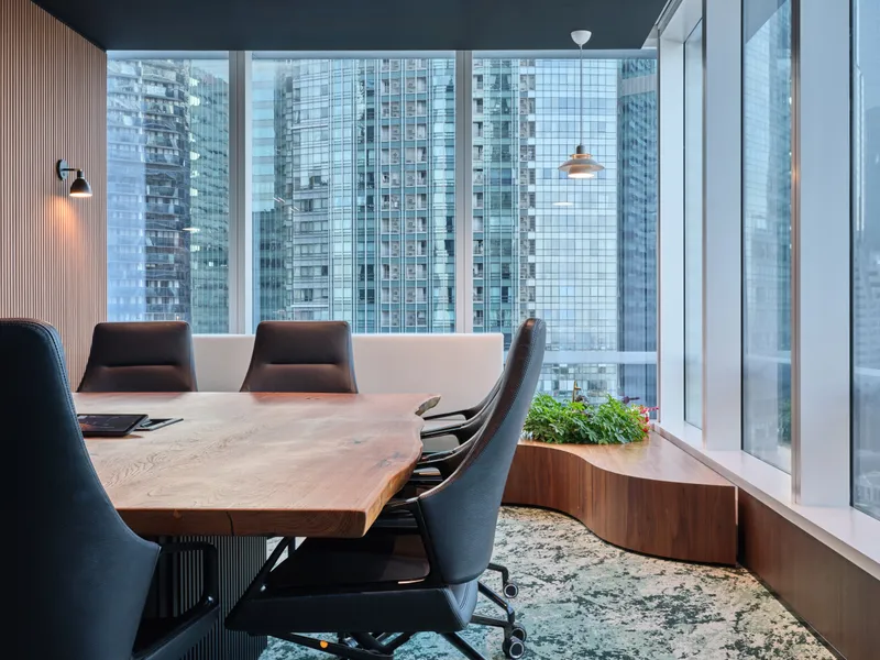 View into a modern boardroom through an open door, showing the seamless connection between formal meeting spaces and office hallways.