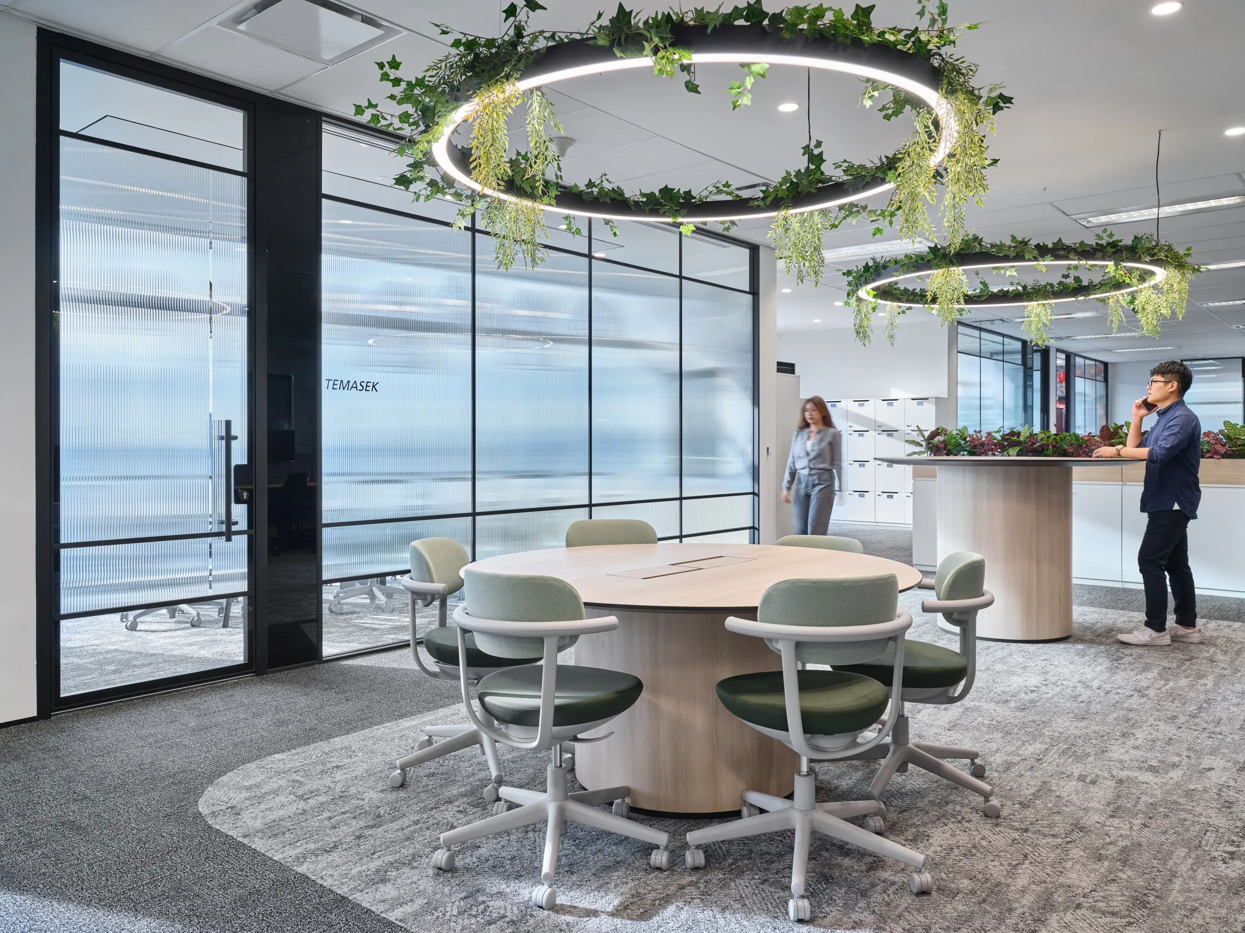 Collaborative zone with green chairs, planter islands and LED ring chandeliers — Singapore workplace photography